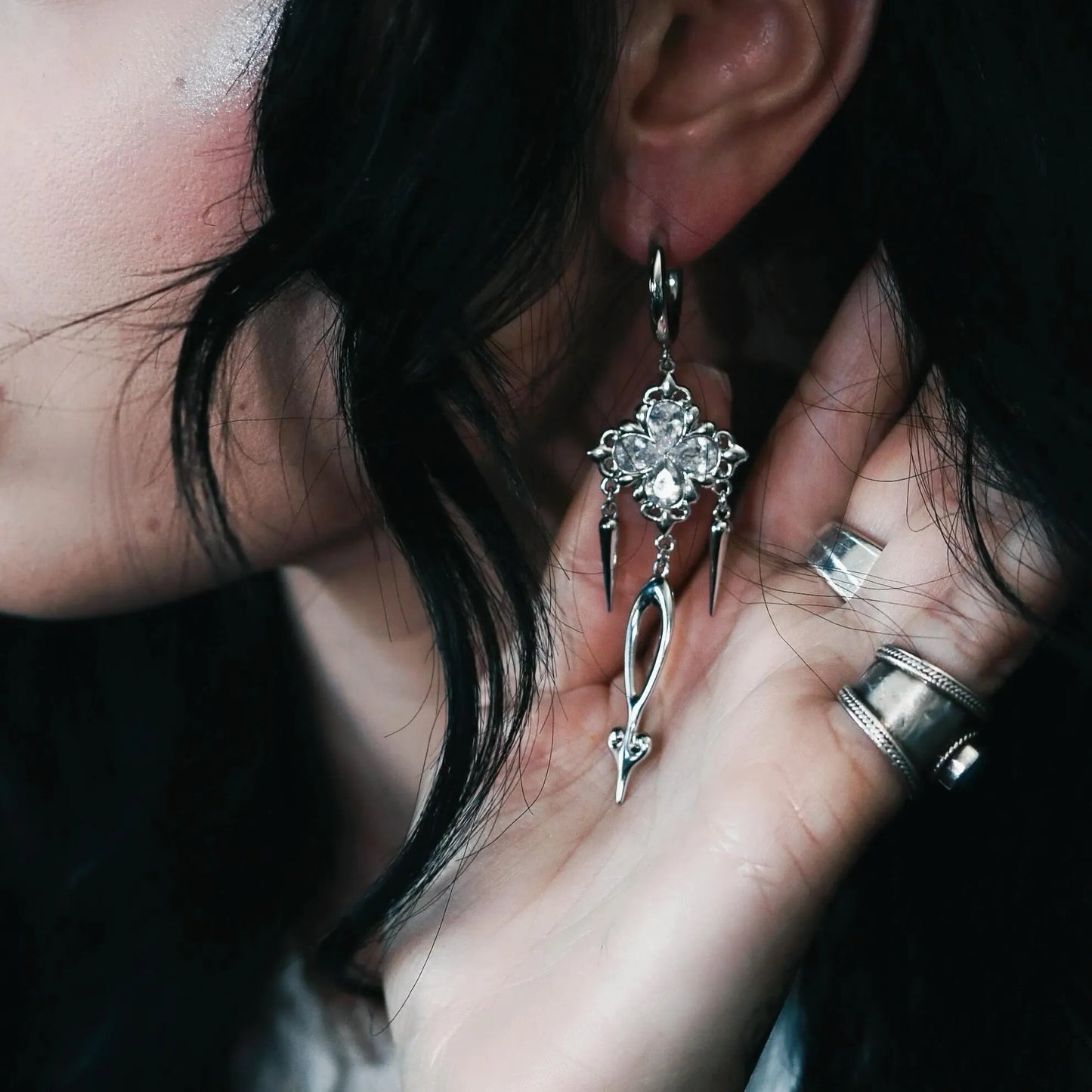 Model wearing Gothic Bloom Earrings featuring a dark floral cluster design with black stones and dangling spike details, styled in a polished hoop silhouette for a bold gothic aesthetic.