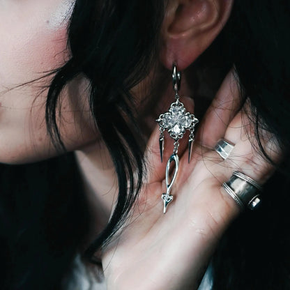 Model wearing Gothic Bloom Earrings featuring a dark floral cluster design with black stones and dangling spike details, styled in a polished hoop silhouette for a bold gothic aesthetic.