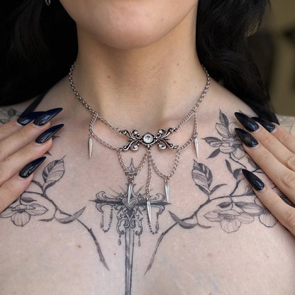 gothic cascade necklace shown on a model, featuring ornate scrollwork, layered chains, pointed drops, and a zircon centerpiece in a close-up styling shot