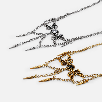 Two necklaces shown side by side, one in silver-tone and one in gold-tone, both with filigree centerpieces and spike charms