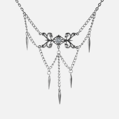 Silver-tone necklace with an ornate filigree centerpiece, clear stone, layered chains, and spike charms