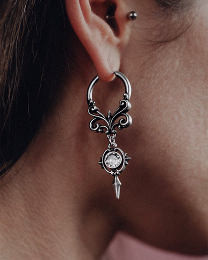 Silver Gothic Crest Earring with clear stone worn on an ear.