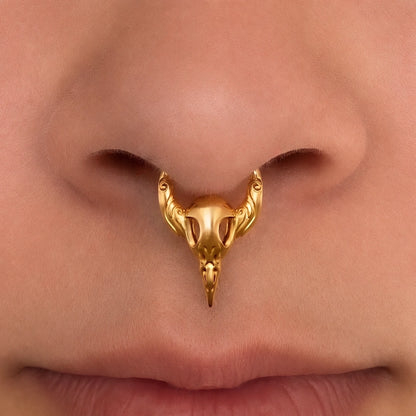 Gold-tone Gothic Raven Clicker worn as a septum ring, showing its pointed raven skull silhouette.