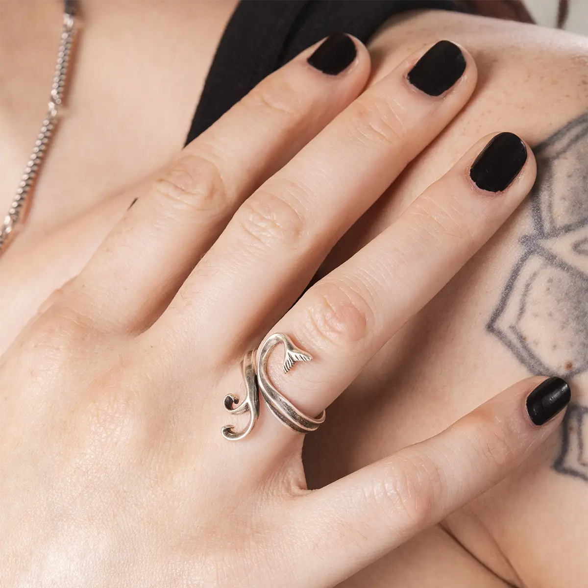 Gothic wave ring in silver styled as an adjustable open ring design on model hand with black nails