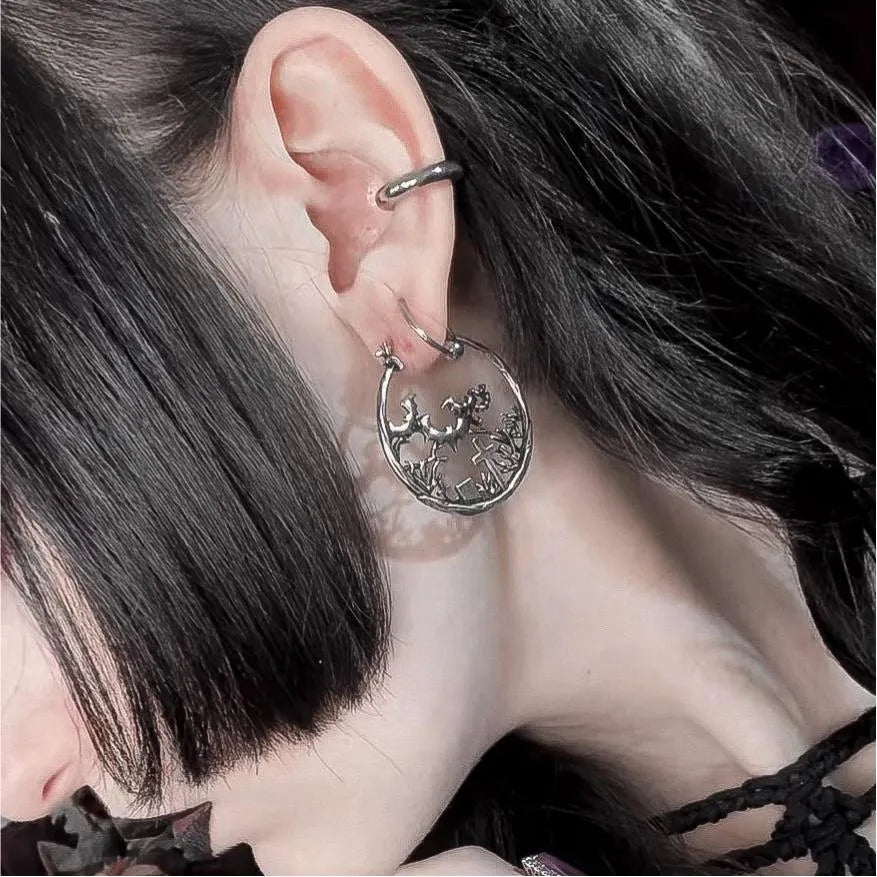 Close-up of an ear with a silver earring and dark hair.