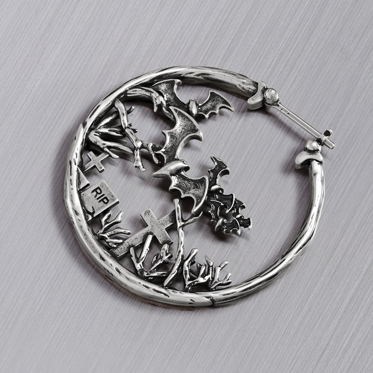 Close-up of silver Graveyard Bat hoop earring with bats and tombstones