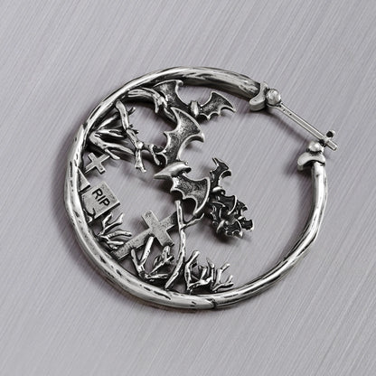 Close-up of silver Graveyard Bat hoop earring with bats and tombstones