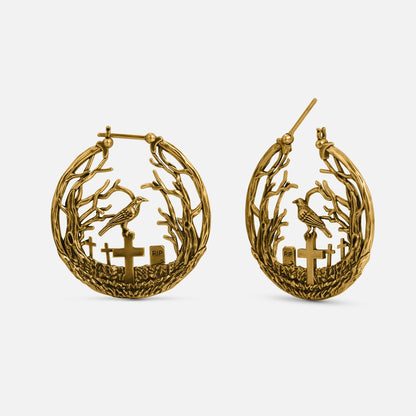 Gold-tone hoop earrings featuring bare branches, a raven, and cross gravestones with RIP marker, front and side view