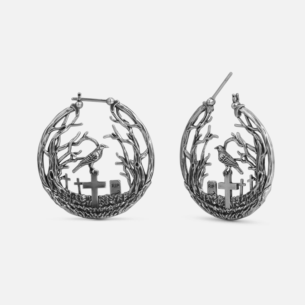 Silver-tone hoop earrings with bare branches, a perched raven, and cross gravestones, front and side view