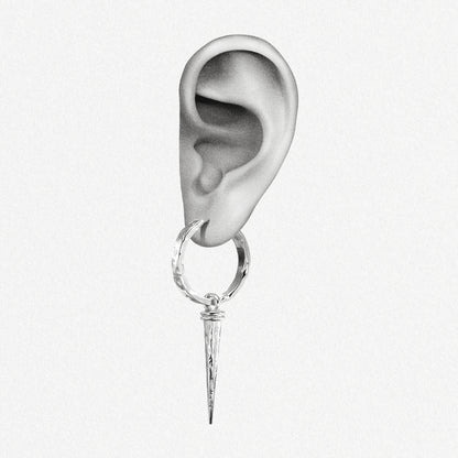 Close-up of an ear wearing a silver-tone hammered hoop earring with a tapered spike drop