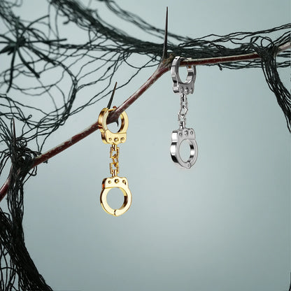 Gold and silver Handcuff Chain earrings hanging from a dark branch