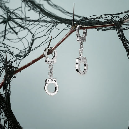 Pair of silver Handcuff Chain earrings hanging from a dark branch