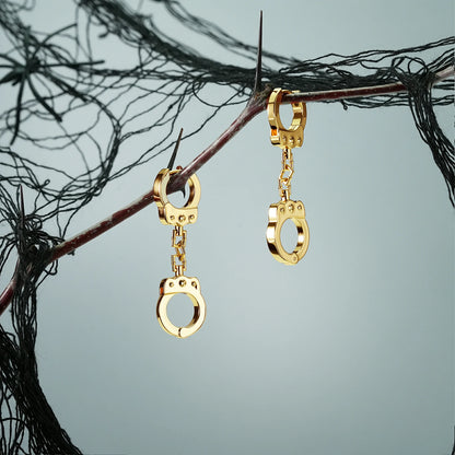 Pair of gold Handcuff Chain earrings hanging from a dark branch