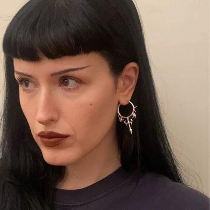 hellflame blade earrings shown on a model in front view, featuring silver hoop earrings with curved flame details and blade drops