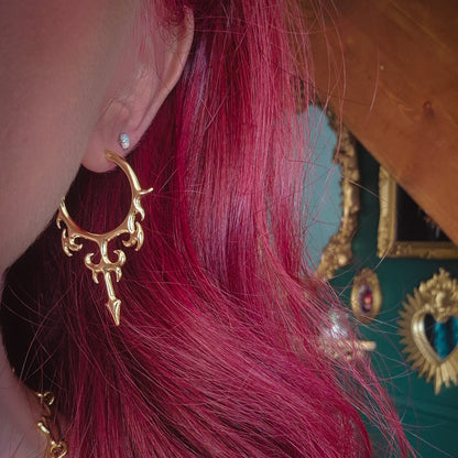 Close-up of gold Hellflame Blade hoop earring worn on the earlobe