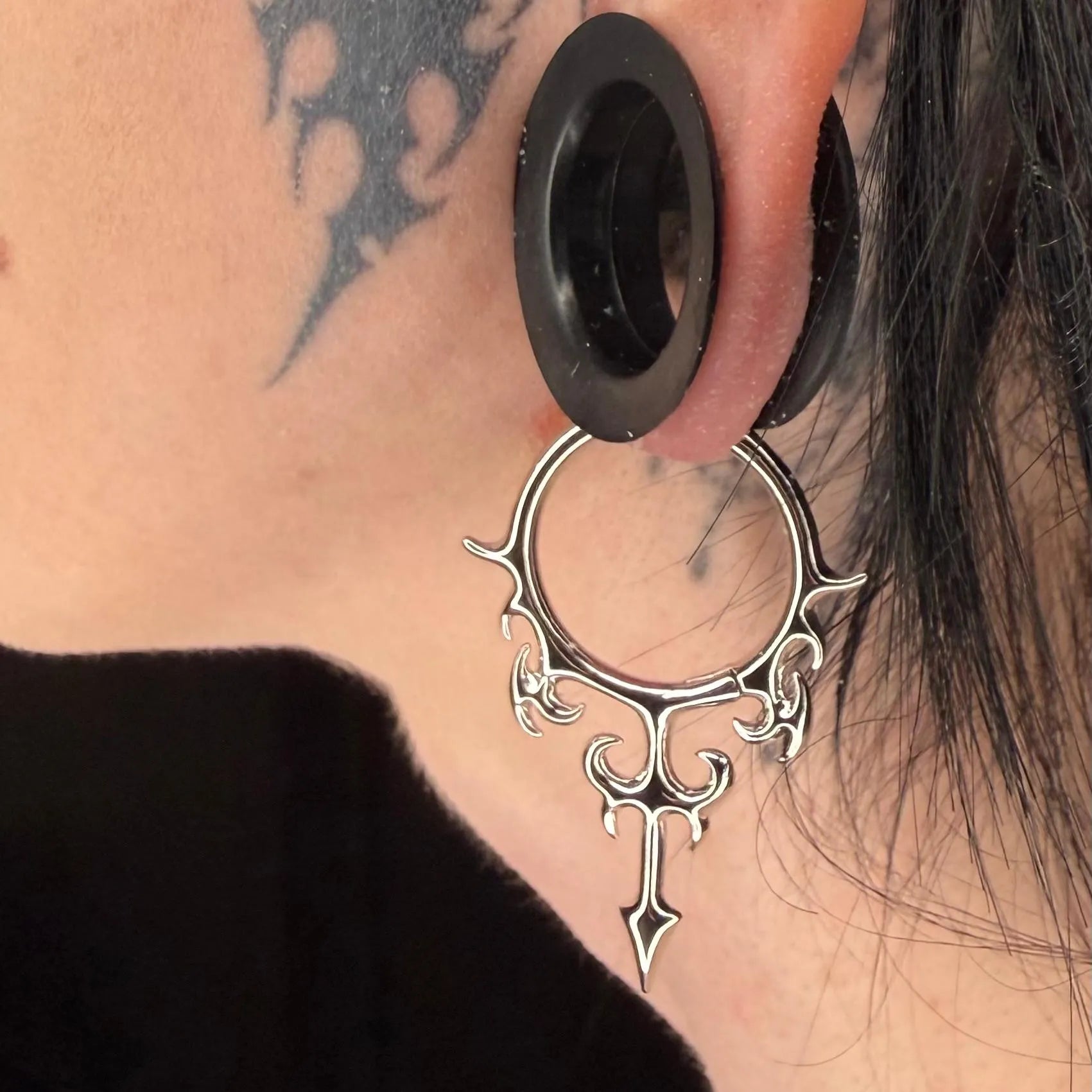 Model wearing the silver Hellflame Blade Earrings with flame-like curves, pointed blade drop, and bold gothic ear styling.