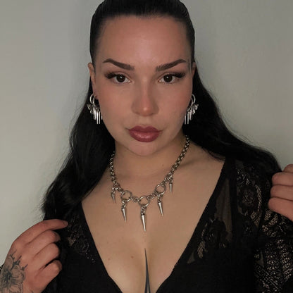 Woman wearing a black lace top with a deep neckline, posing against a plain background.