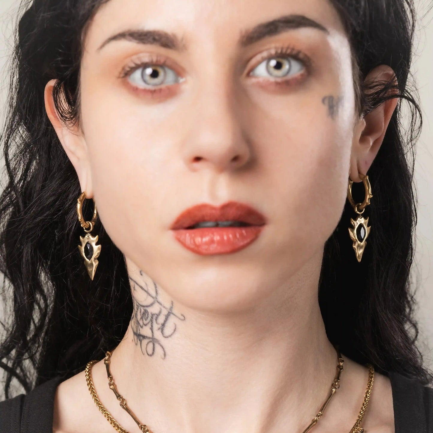 Model wearing gold Knapped Stone Earrings with obsidian arrowhead drops and antiqued finish