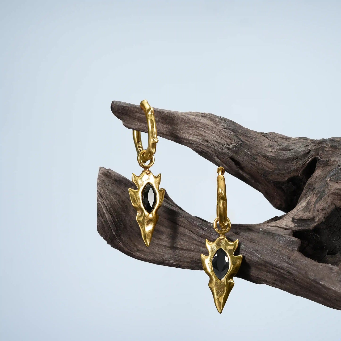 Gold Knapped Stone Earrings displayed on driftwood with black obsidian arrowhead drops