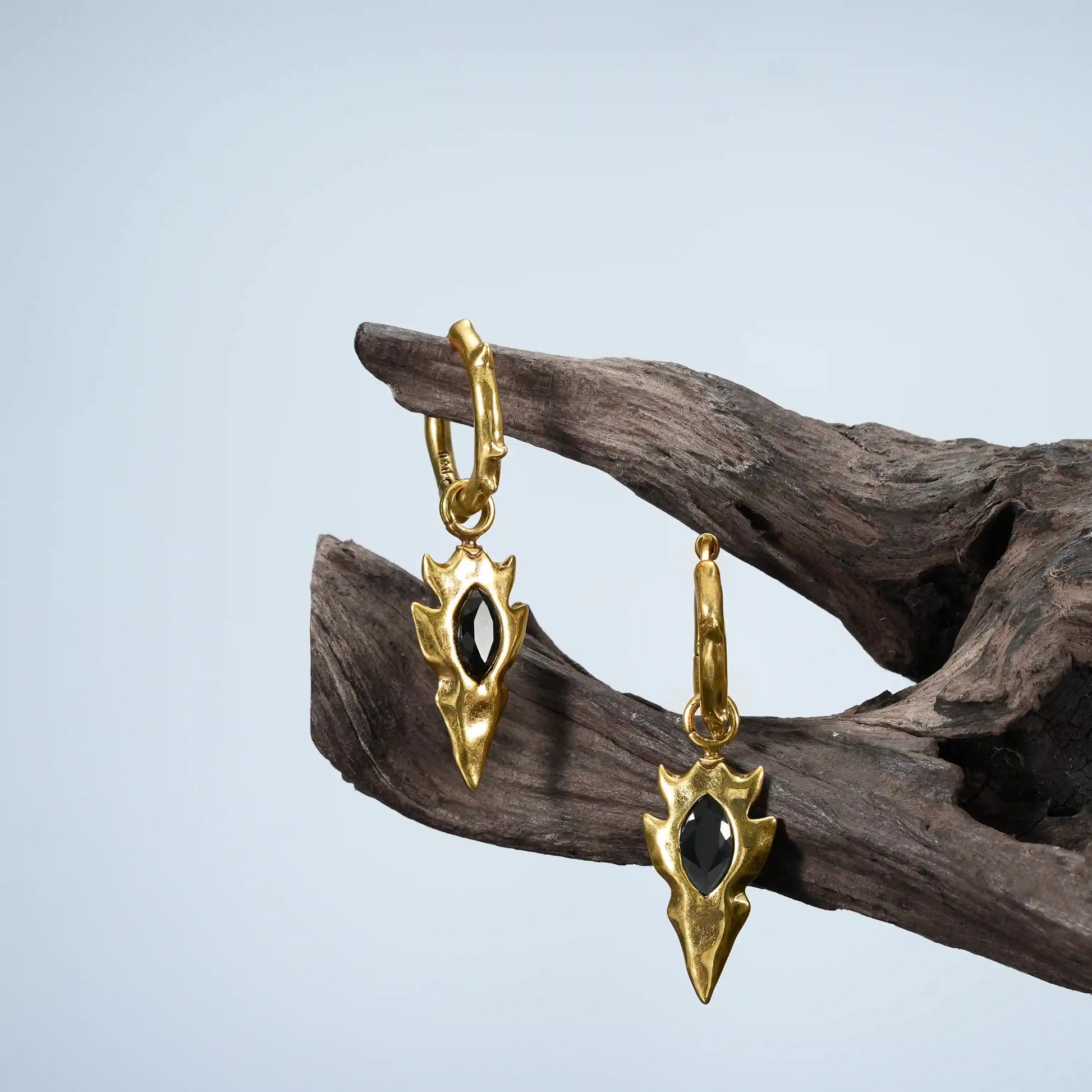 Gold Knapped Stone Earrings displayed on driftwood with black obsidian arrowhead drops