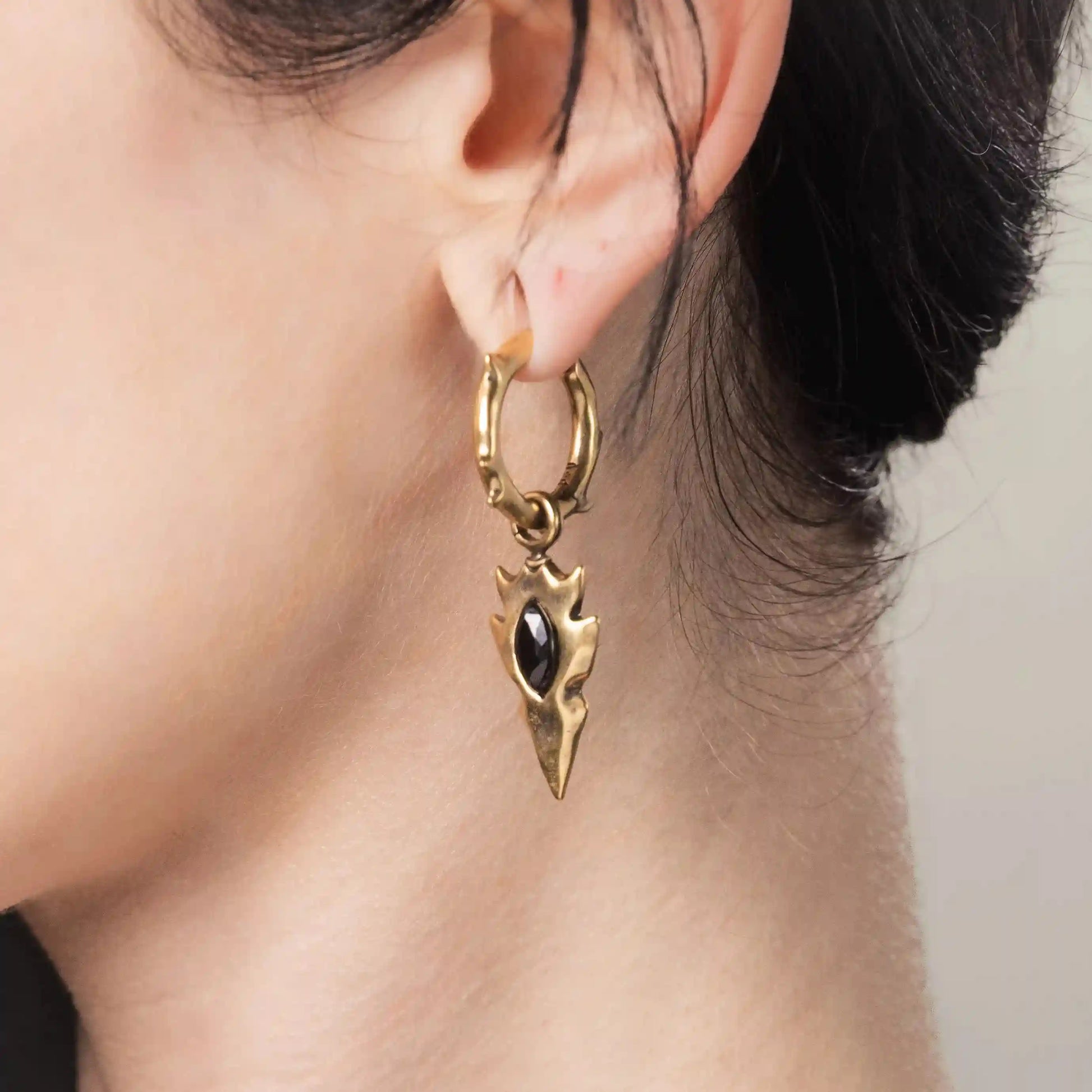 Model wearing gold Knapped Stone Earrings with black obsidian arrowhead drops and hammered hoops