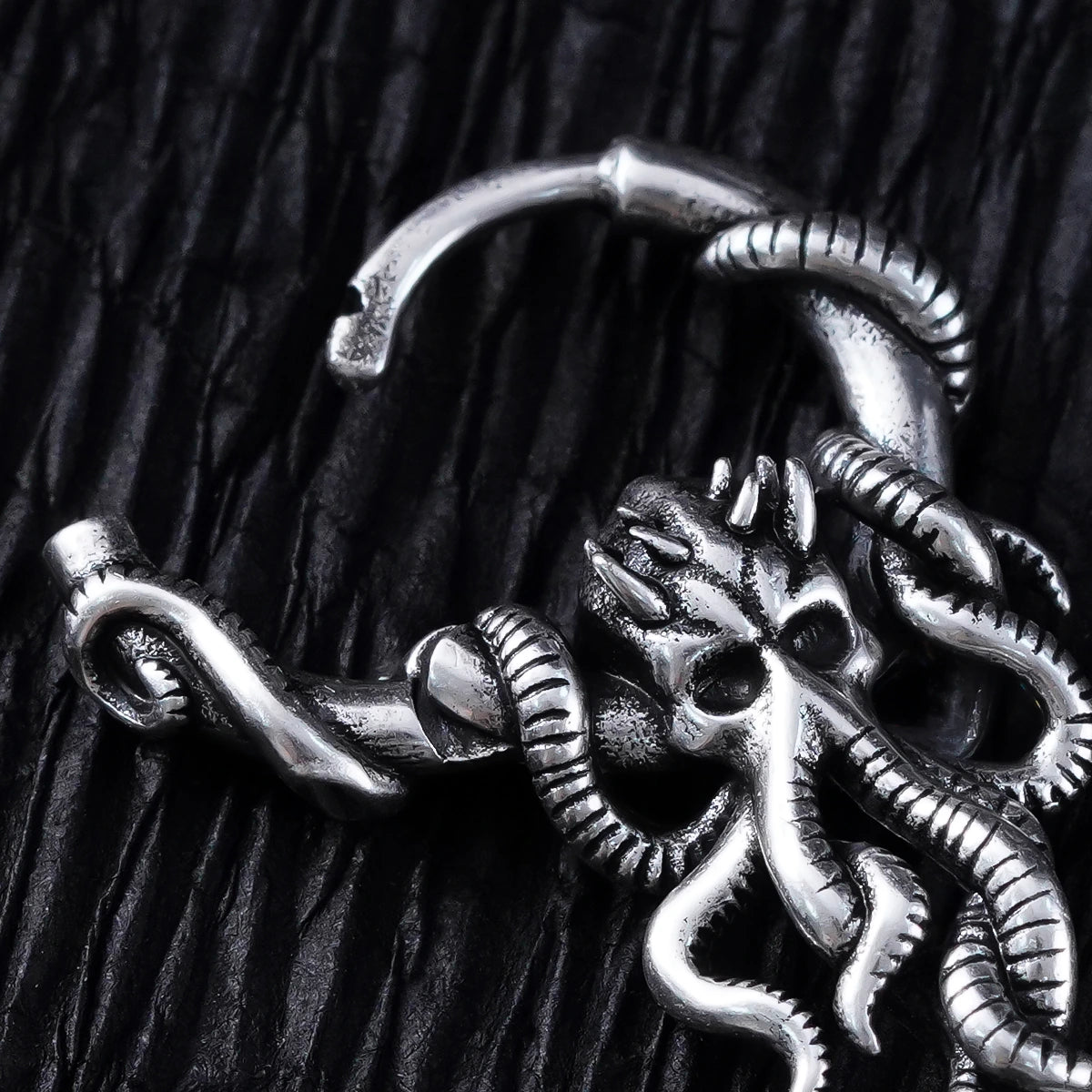 Close-up of a silver-tone hoop earring showing a detailed kraken skull and tentacle design