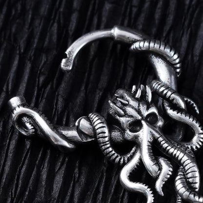 Close-up of a silver-tone hoop earring showing a detailed kraken skull and tentacle design