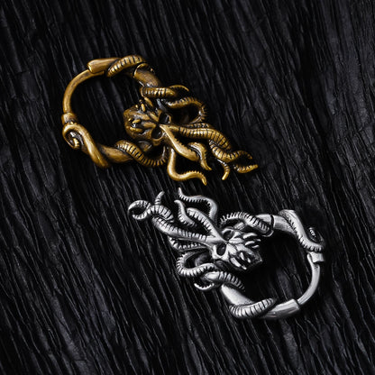 Gold-tone and silver-tone kraken hoop earrings laid on dark textured fabric