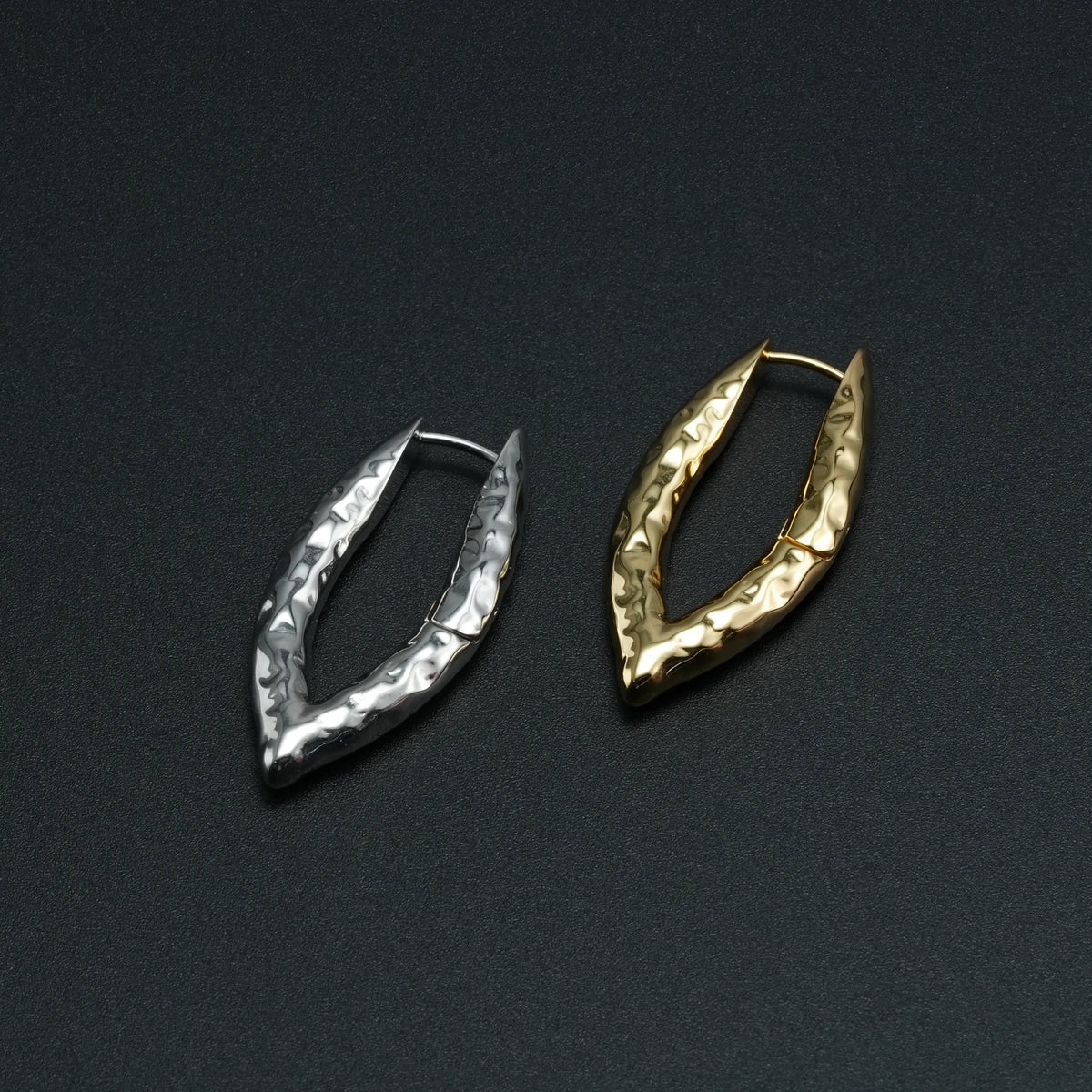 Silver and gold Liquid Metal earrings displayed on a black surface