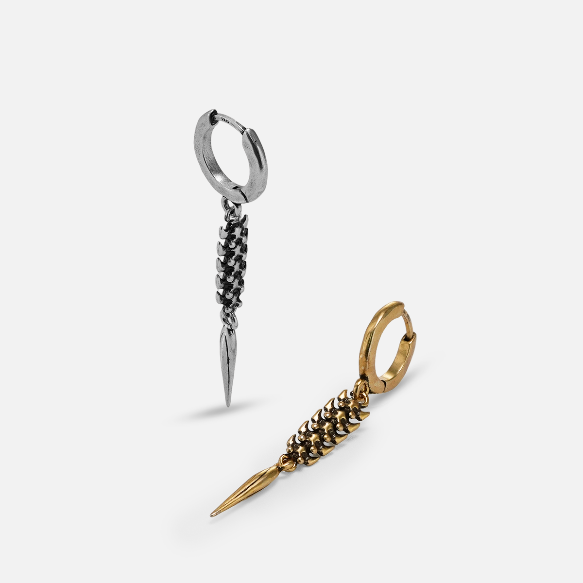 Silver-tone and gold-tone hoop earrings with segmented spine drops laid side by side