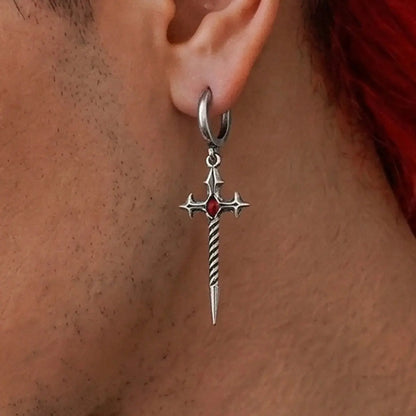 Longinus Godpiercer Earrings in 925 sterling silver, worn in a clean ear close-up on medium skin, showing the red stone and t