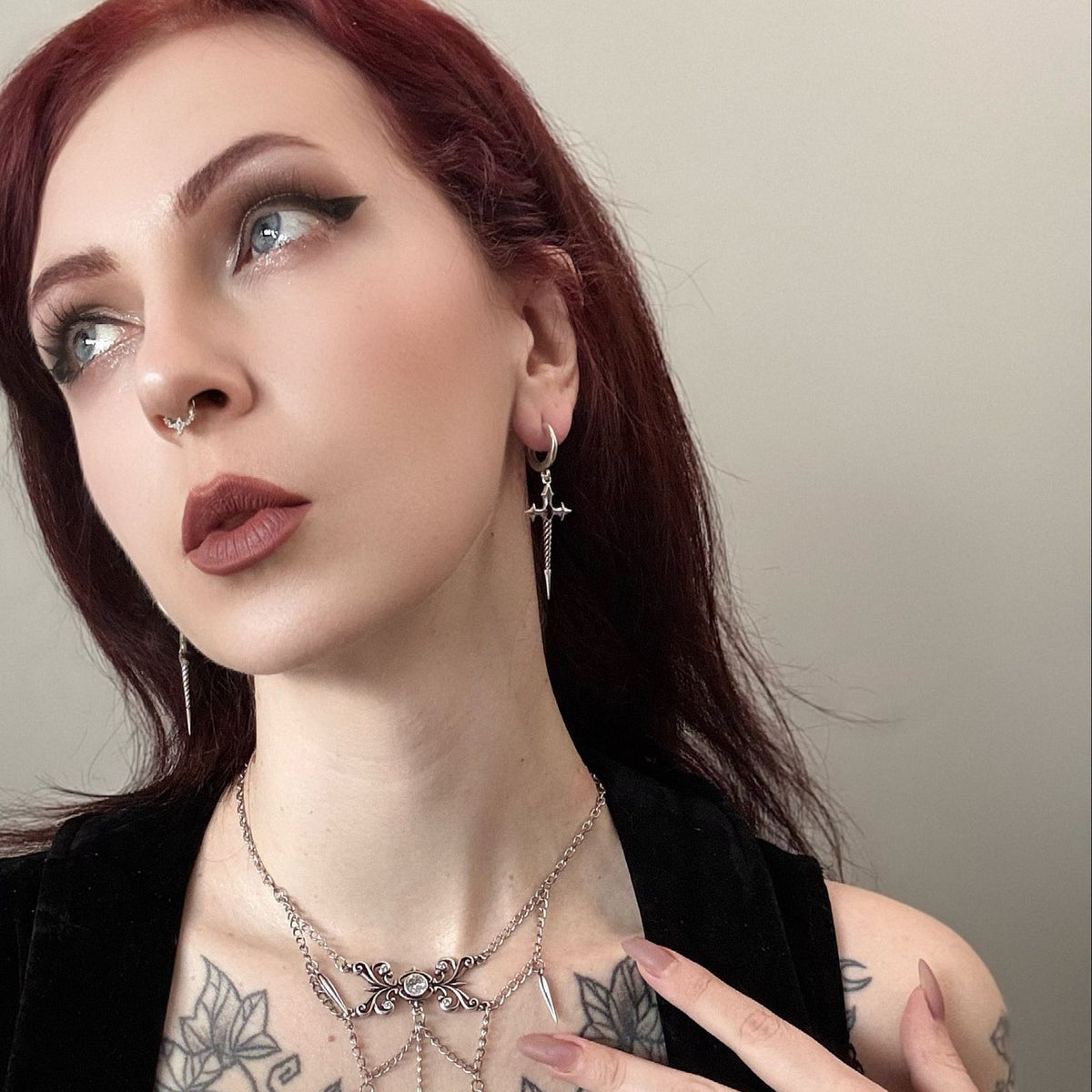 Longinus Godpiercer Earrings in 925 sterling silver, worn in a red-haired portrait with layered silver necklaces and visible 