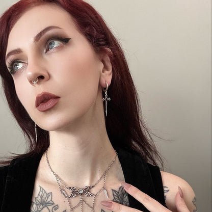 Longinus Godpiercer Earrings in 925 sterling silver, worn in a red-haired portrait with layered silver necklaces and visible 