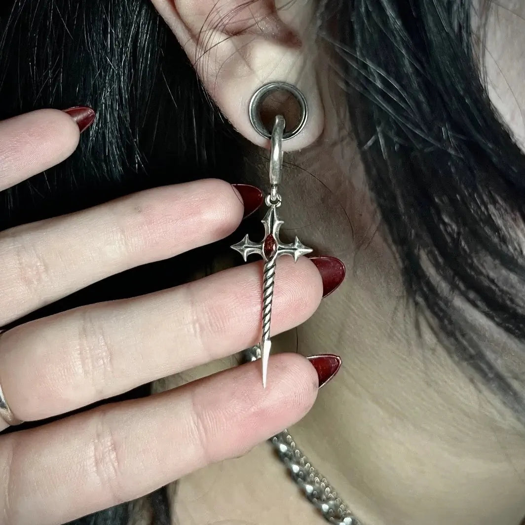 Longinus Godpiercer Earrings in 925 sterling silver, worn from a stretched lobe plug in a close-up with a hand framing the re