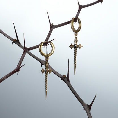 Two gold-tone Longinus Godpiercer sword hoop earrings hanging from dark thorn branches
