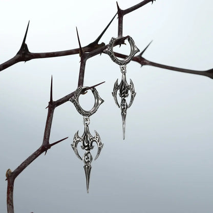 Longinus Halo Piercer Earrings in 925 sterling silver, pair hanging from thorn branches to emphasize the sharp spear silhouet