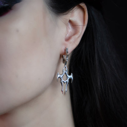 Close-up of a silver-tone talon drop earring worn on a spiked hoop, seen from the side profile