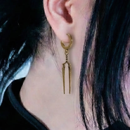 Gold-tone Longinus Twin Spear hoop earring worn in side profile against dark hair