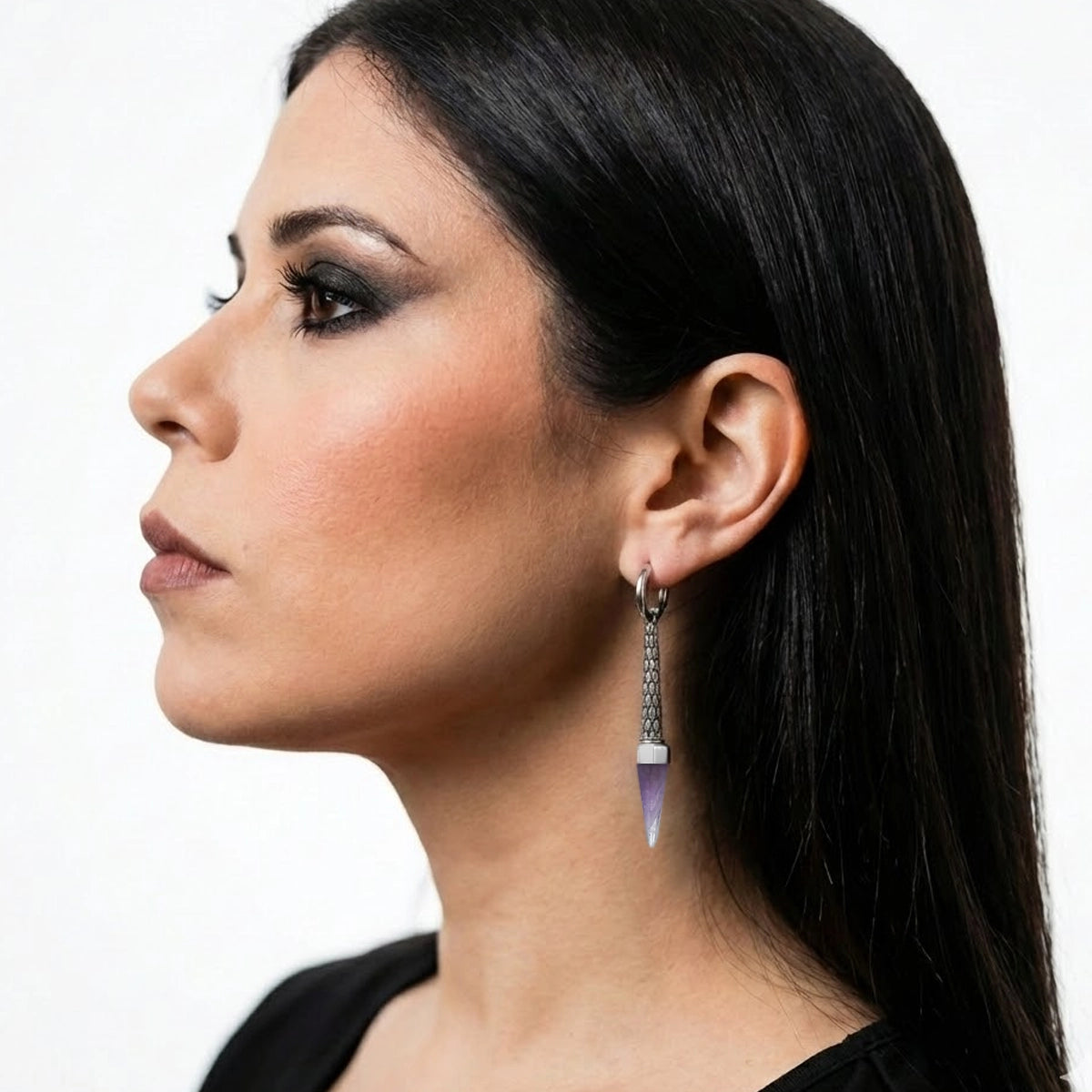Model wearing a dangling hoop earring with a textured bar and light purple pointed crystal drop