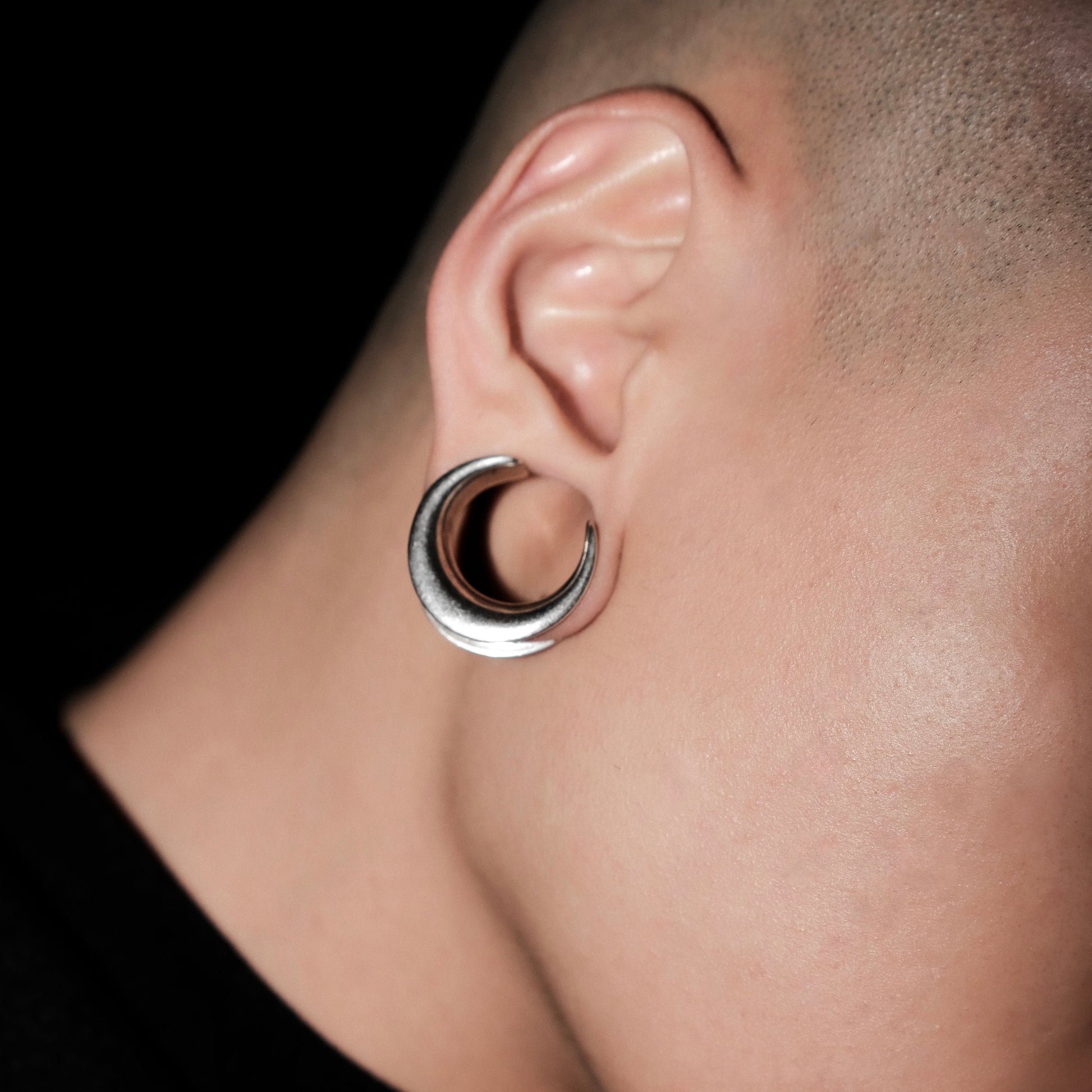 Close-up of silver Lunar Eclipse tunnel worn in a stretched earlobe