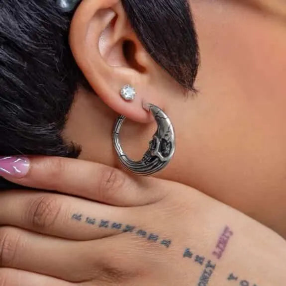 Silver Lunar Solar Skulls Earrings worn on ear with moon skull hoop and gothic celestial design