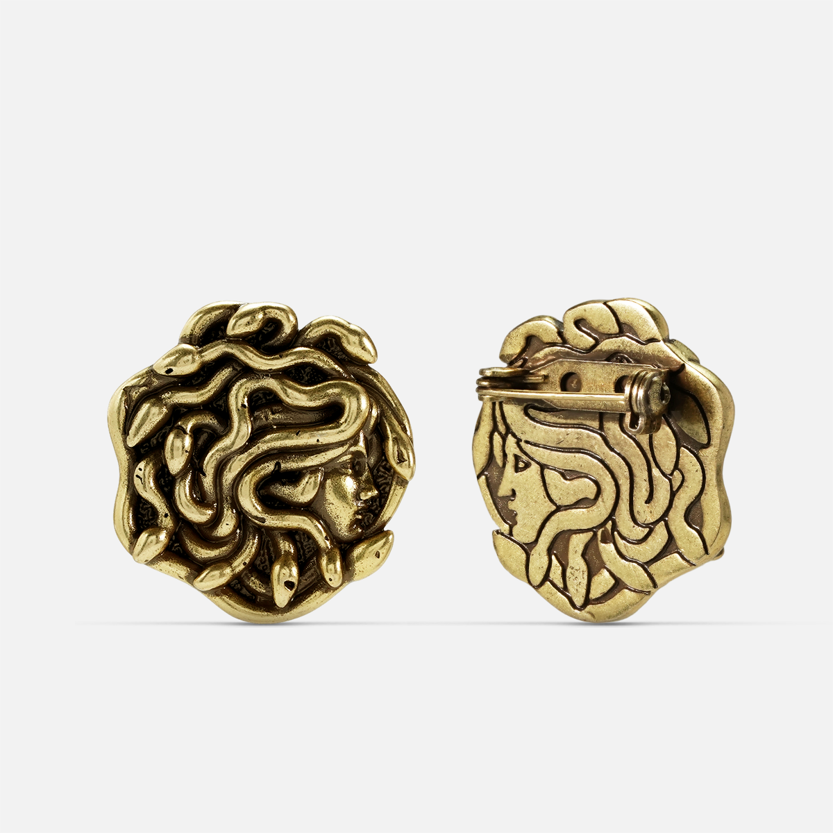 medusa unbound brooch in gold shown in front and back views,featuring a medusa-inspired brooch with sculptural snake details and a pin clasp on the reverse