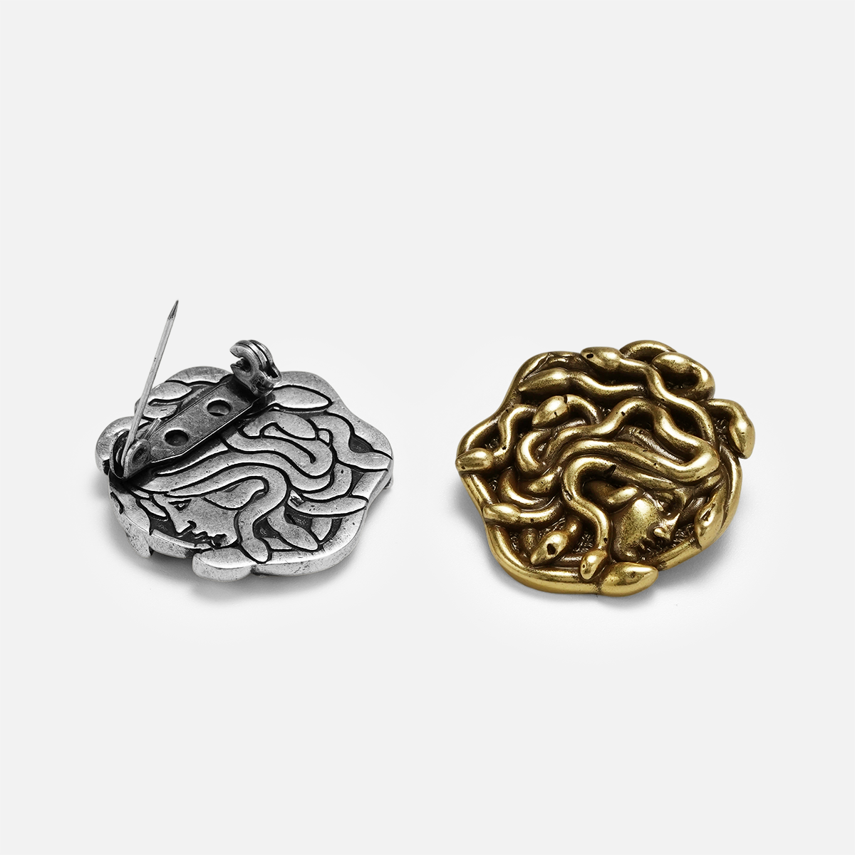 medusa unbound brooch shown in a product view with the gold front and silver back, featuring a sculpted medusa face design and pin closure