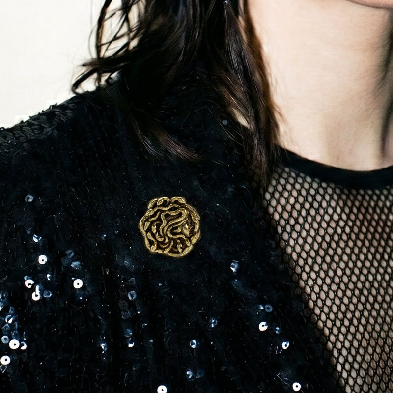 model wearing medusa unbound brooch in gold, featuring a medusa-inspired face formed by sculpted snake details