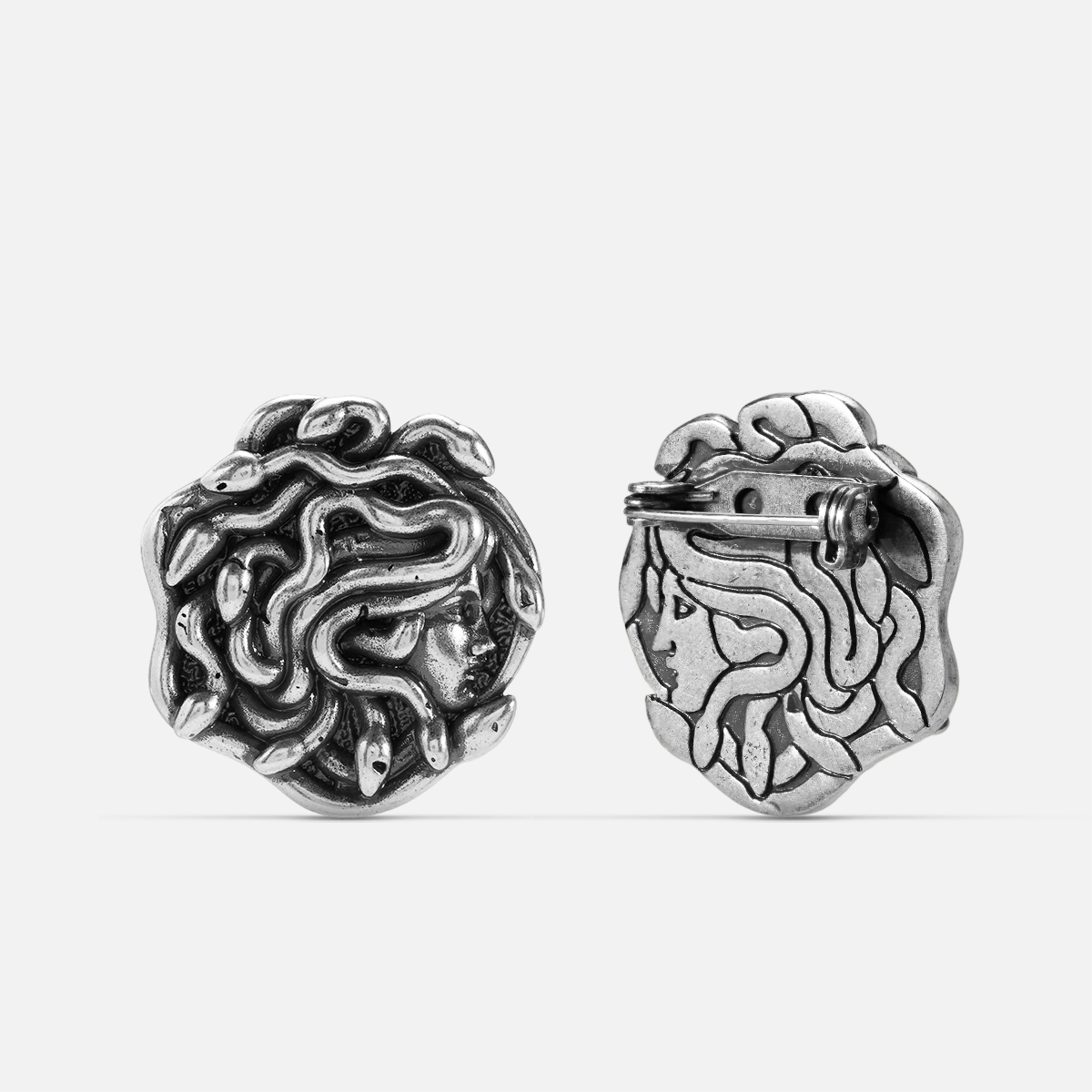 medusa unbound brooch in silver shown in front and back views,featuring a medusa-inspired brooch with sculptural snake details and a pin clasp on the reverse