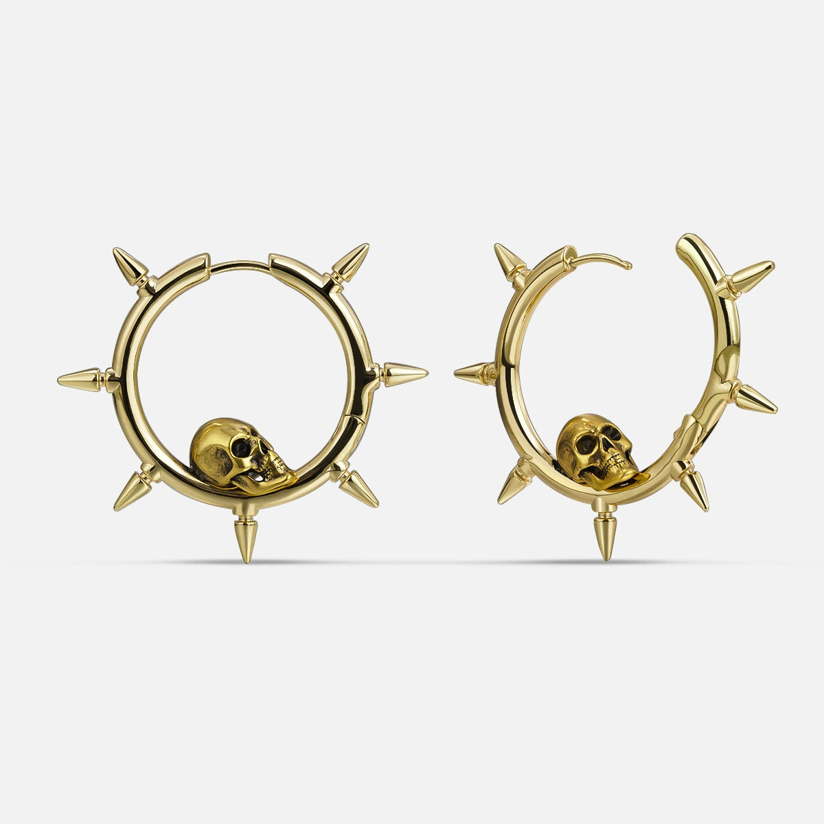 Gold-tone spiked hoop earrings featuring a skull charm nestled within each hoop