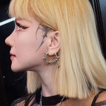 Side profile of model with blonde hair wearing a spiked skull hoop earring and layered earrings