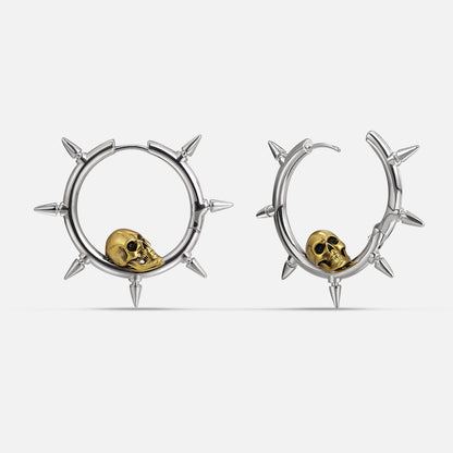 Silver-tone spiked hoop earrings with a gold-tone skull charm resting inside each ring