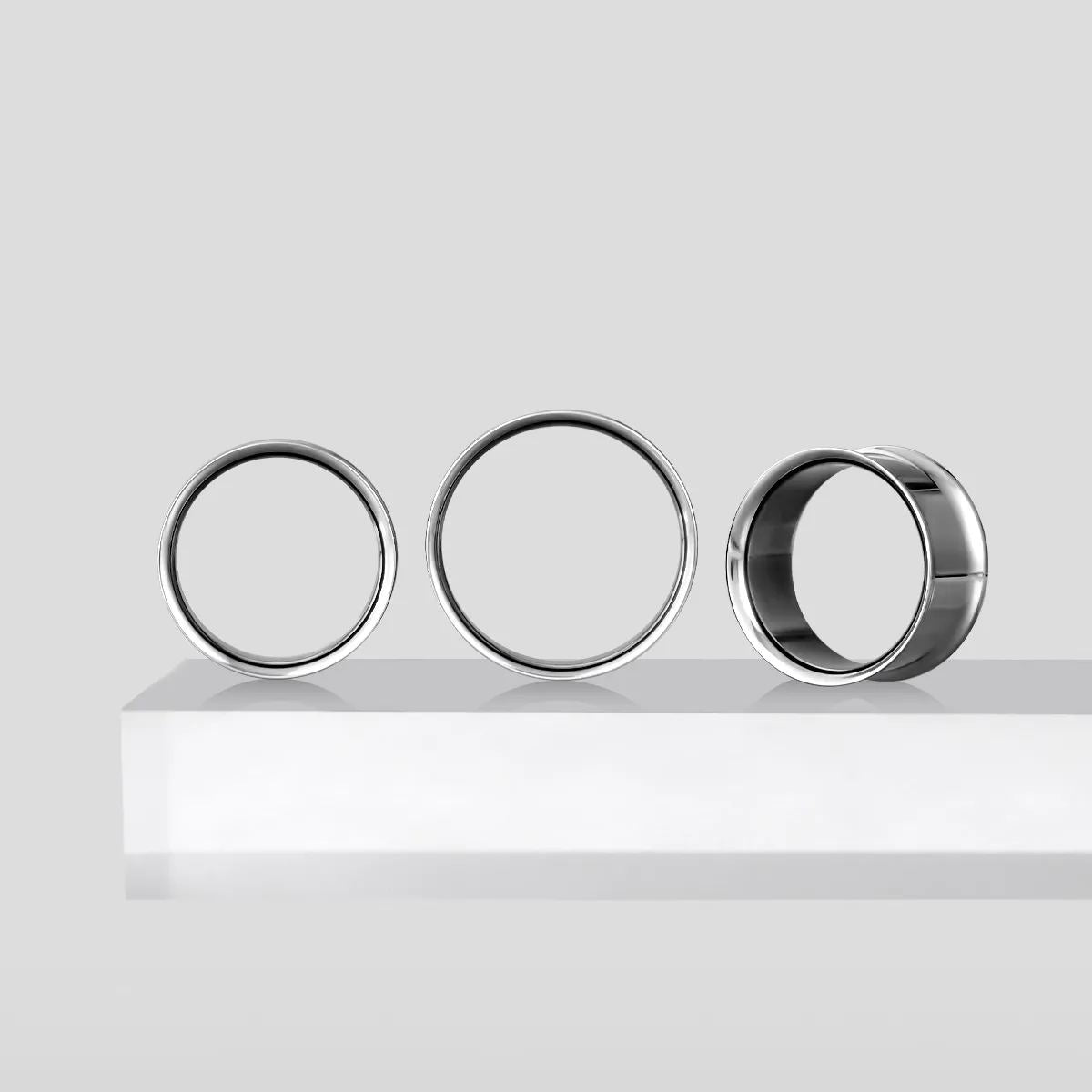 Three titanium loop tunnels arranged upright and tilted on a white ledge