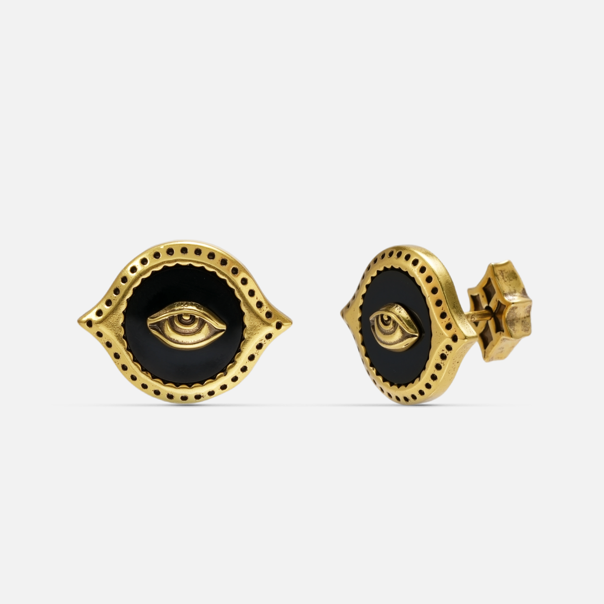 Gold-tone Mirror Witness Stud Earrings shown from front and side views with raised eye motifs and round black obsidian inlays.